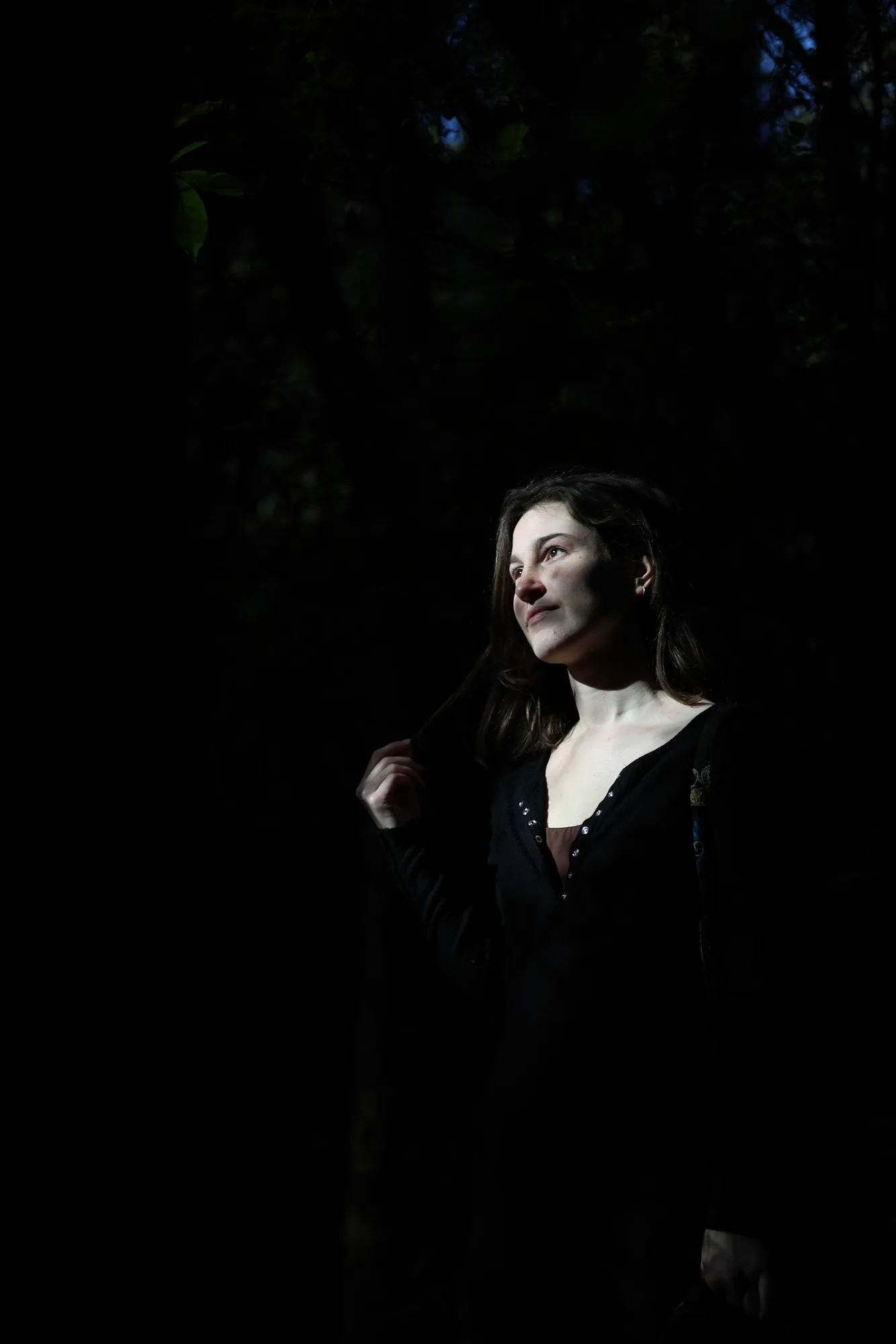A narrow shaft of forest sunlight illuminates Norma against the surrounding shadows